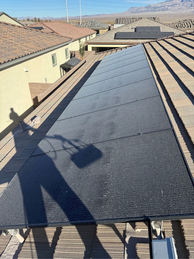 Heavily dust-coated solar panels on a Las Vegas rooftop before professional cleaning — desert grime visibly coating the glass